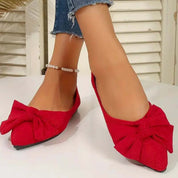 Scarpe ballerine rosse con fiocco, indossate con jeans strappati alla caviglia. Eleganti e alla moda, ideali per look casual e chic.