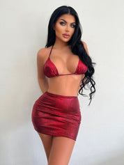 Modella in bikini rosso lucido con stampa serpente, posa contro sfondo bianco. Moda estiva, abbigliamento da spiaggia, tendenze 2023.