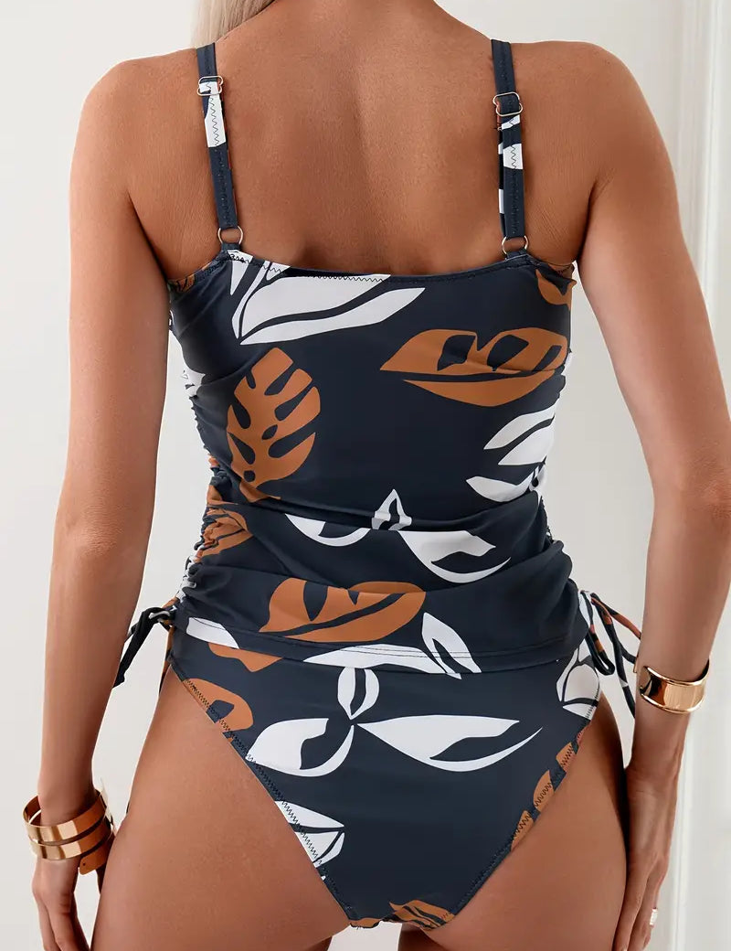Costume intero donna con stampa foglie tropicali, spalline regolabili, colore blu scuro e marrone, moda mare estate 2023.