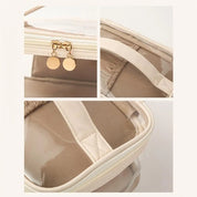 Borsa trasparente in PVC beige con dettagli dorati, chiusura a zip e manici rinforzati. Design elegante e pratico per moda e viaggi.
