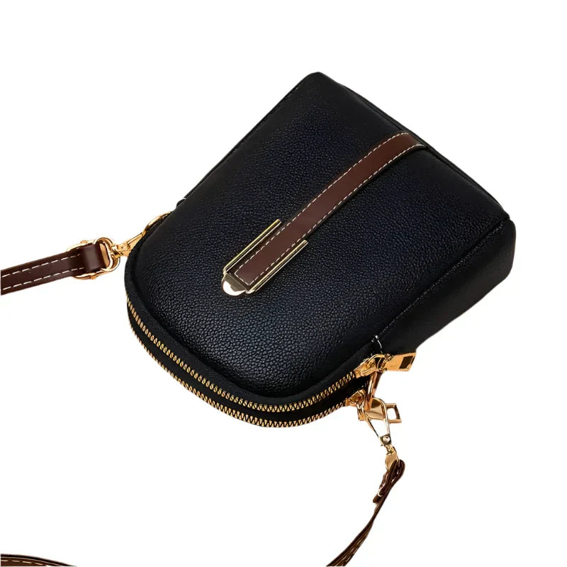 Borsa a tracolla in pelle nera con dettagli dorati e cinturino marrone, design elegante e compatto, ideale per moda femminile e accessori di lusso.