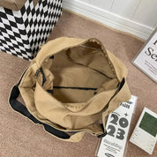 Borsa a tracolla beige in tela aperta su tappeto marrone, con tasca interna nera. Accanto, calendario 2023 e orologio digitale.