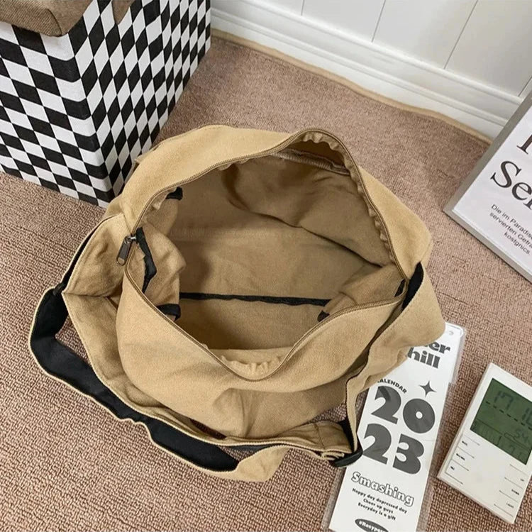 Borsa a tracolla beige in tela aperta su tappeto marrone, con tasca interna nera. Accanto, calendario 2023 e orologio digitale.