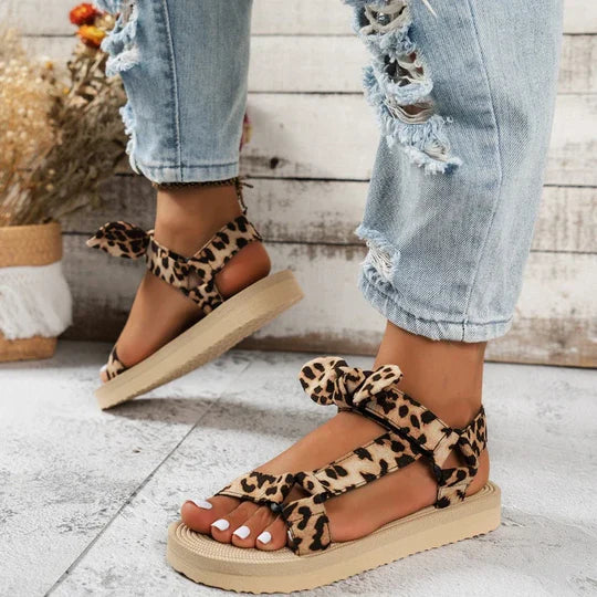 Sandali donna leopardati con suola piatta, indossati con jeans strappati. Moda estiva, calzature casual eleganti, stile trendy.