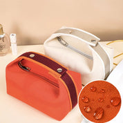 Due astucci impermeabili in tessuto, uno arancione e uno beige, con cerniera e bottoni. Ideali per cosmetici o accessori da viaggio.
