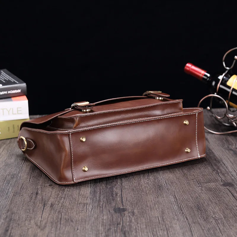 Borsa a tracolla in pelle marrone su tavolo di legno, con dettagli in metallo dorato. Elegante accessorio moda, perfetto per uomo e donna.