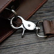 Gancio in metallo lucido su borsa in pelle marrone, dettaglio di alta qualità, accessorio moda elegante, chiusura sicura per borse uomo e donna.