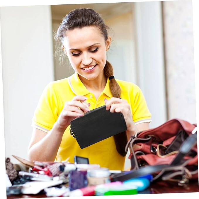 Donna sorridente in maglietta gialla organizza cosmetici in una borsa nera. Trucco, bellezza, accessori, cura personale, moda femminile.