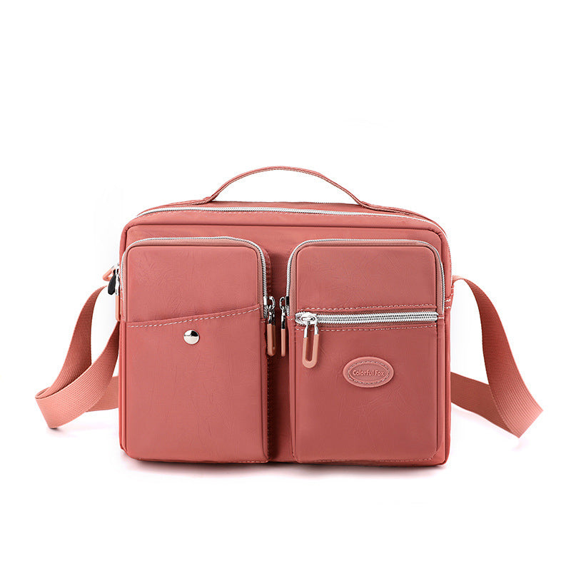 Borsa a tracolla rosa in pelle con tasche multiple e cerniere, design elegante e funzionale, ideale per donna. Accessorio moda versatile.