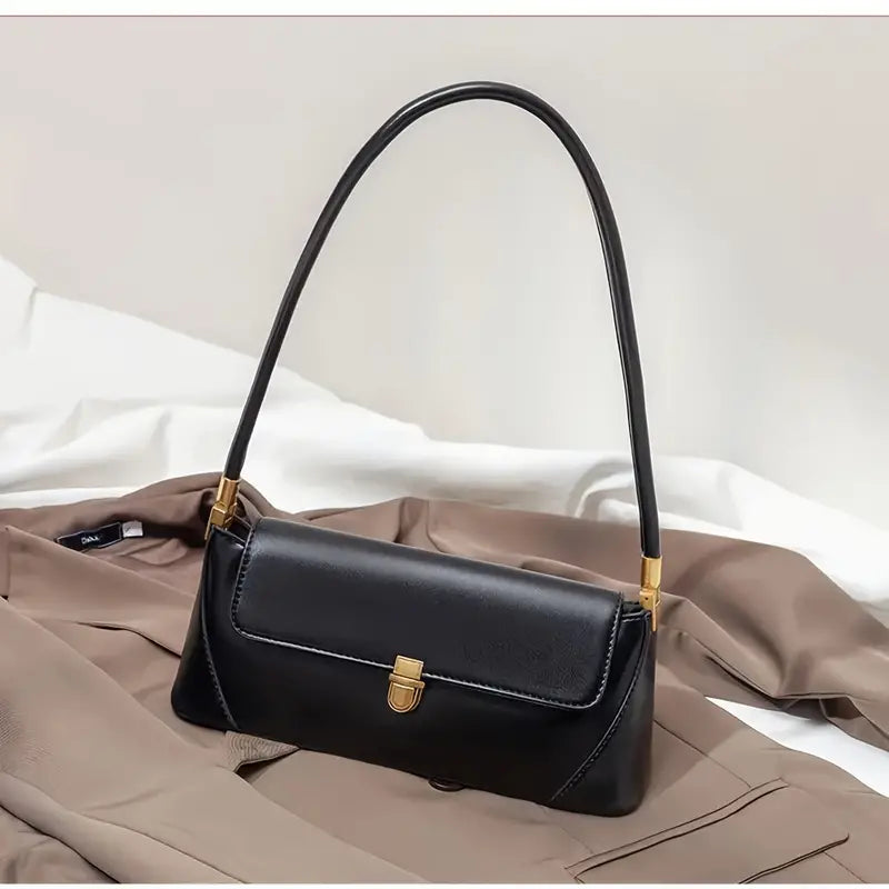 Borsa a tracolla nera in pelle su cappotto beige, design elegante con chiusura dorata. Accessorio moda donna, stile sofisticato e moderno.
