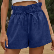 Shorts a vita alta blu in denim con cintura arricciata e laccio, indossati da una donna. Moda estiva casual, abbigliamento femminile trendy.