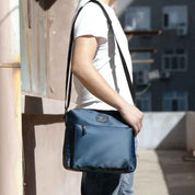Borsa a tracolla uomo in pelle blu, design moderno, tasca frontale con zip, ideale per lavoro e viaggio. Accessorio moda maschile elegante.