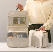 Borsa da toilette beige aperta e chiusa, con gancio, tasche a rete e prodotti da viaggio. Ideale per organizzare cosmetici e accessori.