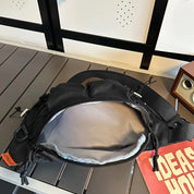 Marsupio nero aperto su tavolo, con cerniere e tasche multiple, ideale per viaggi e attività all'aperto. Design moderno e funzionale.