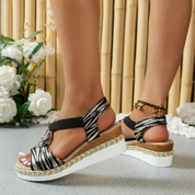 Sandali con zeppa donna, motivo zebrato, suola bianca spessa, cinturino elastico nero, sfondo floreale. Scarpe estive eleganti e comode.