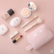 Set di cosmetici su sfondo rosa: fondotinta, cipria, rossetto rosso, pennelli trucco, crema viso, pochette rosa. Accessori bellezza essenziali.