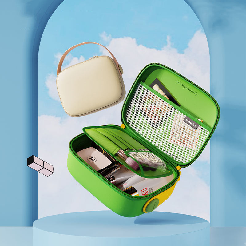 Astuccio da viaggio verde aperto con accessori per trucco, specchio e tasca a rete, accanto a borsa beige con manico, sfondo cielo blu.