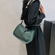Donna con borsa a tracolla verde, abito nero elegante. Accessorio moda femminile, stile casual chic. Tendenza borse 2023.