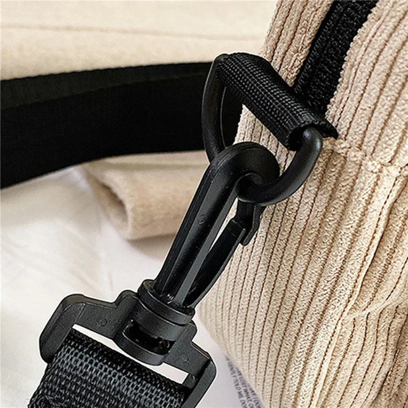 Gancio in plastica nera su borsa a tracolla beige in tessuto a coste. Accessorio moda, dettaglio chiusura sicura. Borsa casual elegante.