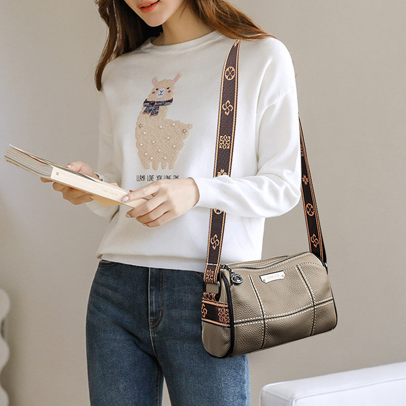 Donna con maglione bianco con stampa lama, jeans blu e borsa a tracolla marrone. Accessorio moda casual, stile quotidiano, tendenza autunno.