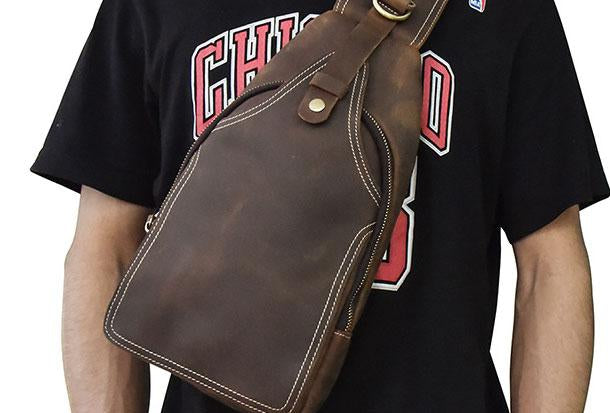 Zaino a tracolla in pelle marrone su uomo con maglietta nera. Design elegante, ideale per moda urbana e viaggi. Accessorio versatile e resistente.