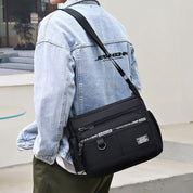 Uomo con giacca di jeans indossa borsa a tracolla nera casual, tasche multiple, stile urbano. Accessorio moda maschile, pratico e versatile.