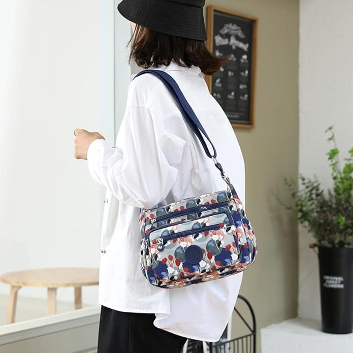 Borsa a tracolla floreale multicolore, indossata da una persona con camicia bianca e cappello nero. Design moderno, ideale per moda casual.