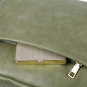 Borsa in pelle verde con chiusura a zip dorata, contenente un portafoglio metallico. Accessorio moda elegante e funzionale per donna.