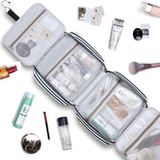 Beauty case da viaggio aperto con scomparti trasparenti, contenente prodotti cosmetici e accessori. Organizzatore trucco portatile, ideale per viaggi.
