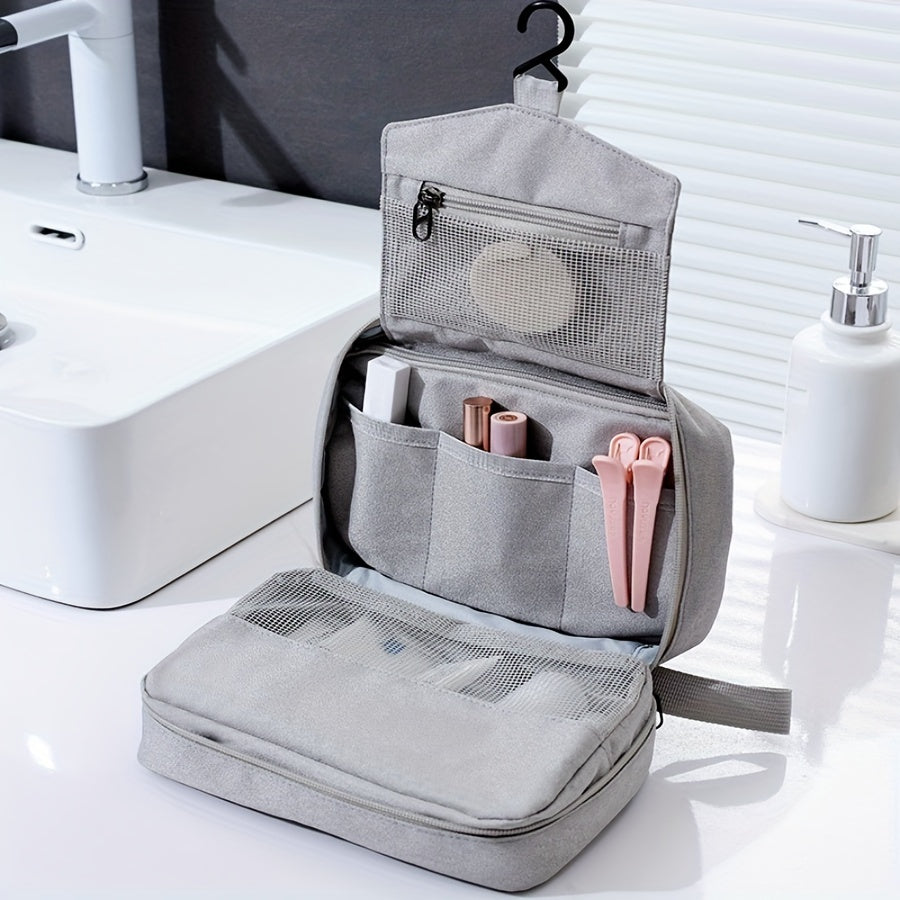 Borsa da toilette grigia aperta su lavandino, con gancio, tasche multiple, contenente articoli da bagno e cosmetici. Organizzatore da viaggio pratico.