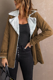 Giacca marrone con interno in pelliccia sintetica bianca, indossata da donna con top nero e jeans neri. Stile casual autunnale.