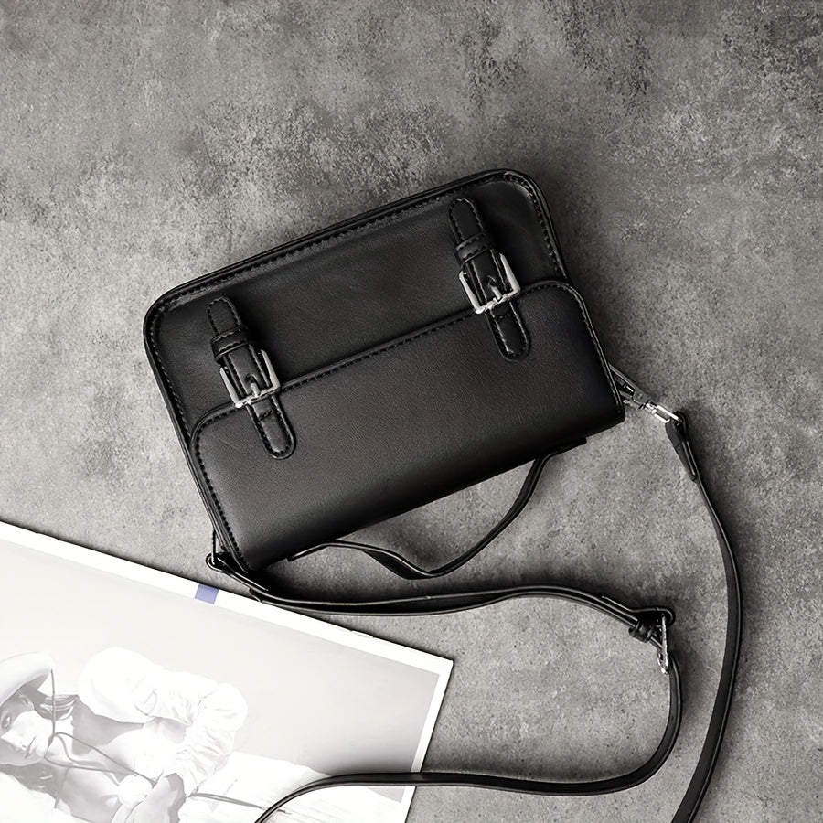 Borsa a tracolla nera in pelle su sfondo grigio, con fibbie decorative e tracolla regolabile. Elegante accessorio moda per donna.