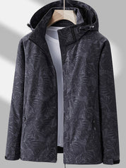 Giacca impermeabile nera con cappuccio, motivo foglie, chiusura zip, tasche laterali, ideale per outdoor e sport. Design moderno e funzionale.