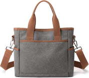 Borsa a tracolla in tela grigia con manici marroni, tasca frontale e tracolla regolabile. Design casual, ideale per uso quotidiano e shopping.