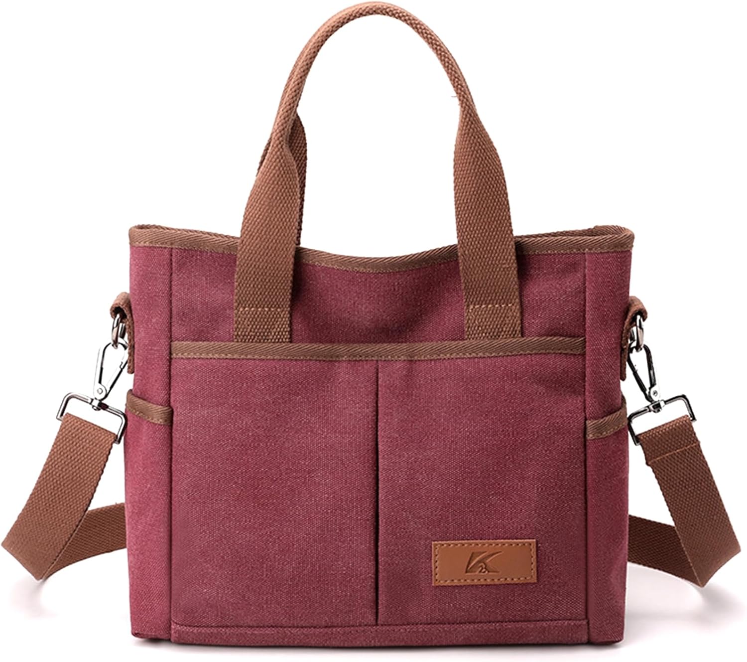 Borsa a tracolla in tela rosa con manici marroni, tasche frontali e tracolla regolabile. Design elegante e pratico per uso quotidiano.