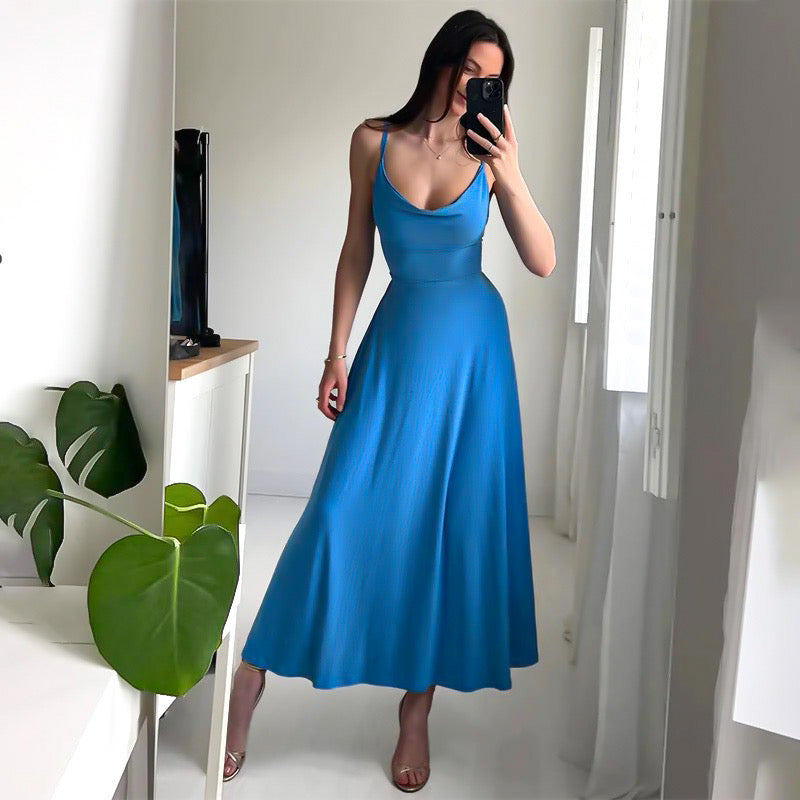 Donna in abito lungo blu, scollo a V, posa davanti a uno specchio. Moda elegante, abbigliamento estivo, stile femminile, tendenze 2023.