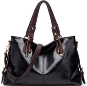 Borsa a mano in pelle nera lucida con manici marroni, dettagli dorati e tracolla regolabile. Elegante accessorio moda donna.