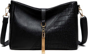 Borsa a tracolla donna in pelle nera con texture coccodrillo, decorazione con nappina dorata, chiusura a zip, elegante e versatile.