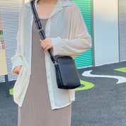 Donna con camicia bianca trasparente e abito beige, borsa a tracolla nera. Moda casual estiva, look urbano, abbigliamento femminile trendy.