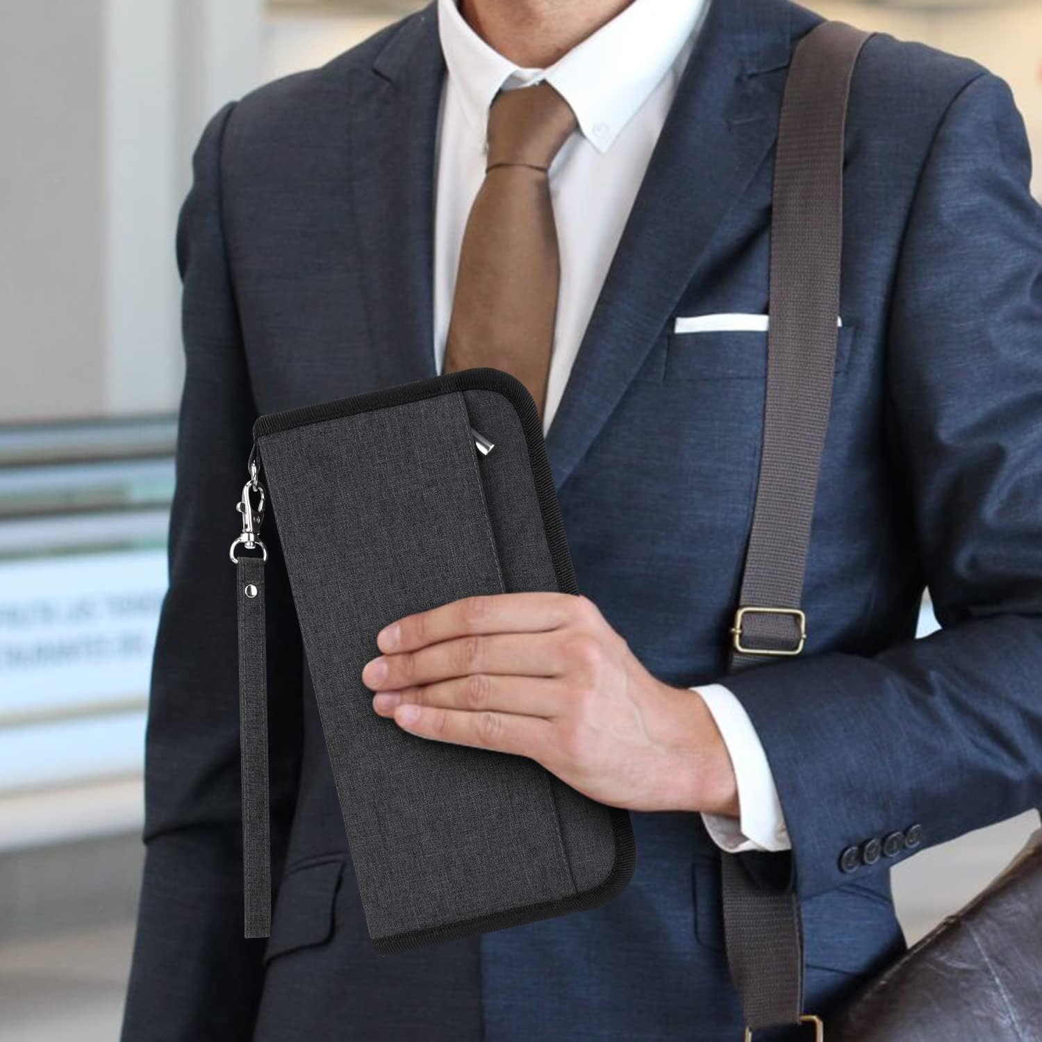 Uomo in abito elegante con portafoglio da viaggio nero in mano, design moderno, ideale per documenti e carte, accessorio business essenziale.