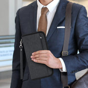 Uomo in abito elegante con portafoglio da viaggio nero in mano, design moderno, ideale per documenti e carte, accessorio business essenziale.