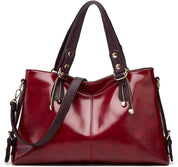 Borsa a mano in pelle rossa lucida con manici marroni, dettagli dorati e tracolla regolabile. Elegante accessorio moda donna.