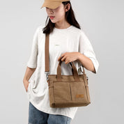 Borsa a tracolla donna in tela marrone, design casual, con manici e tasche frontali. Ideale per uso quotidiano e abbigliamento casual.