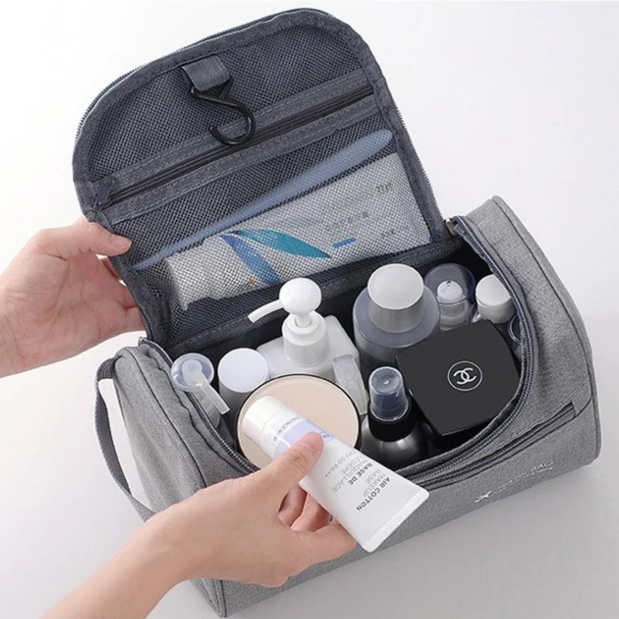 Borsa da toilette grigia aperta con vari prodotti cosmetici e per la cura della pelle, tra cui flaconi e creme. Organizzatore da viaggio pratico e capiente.