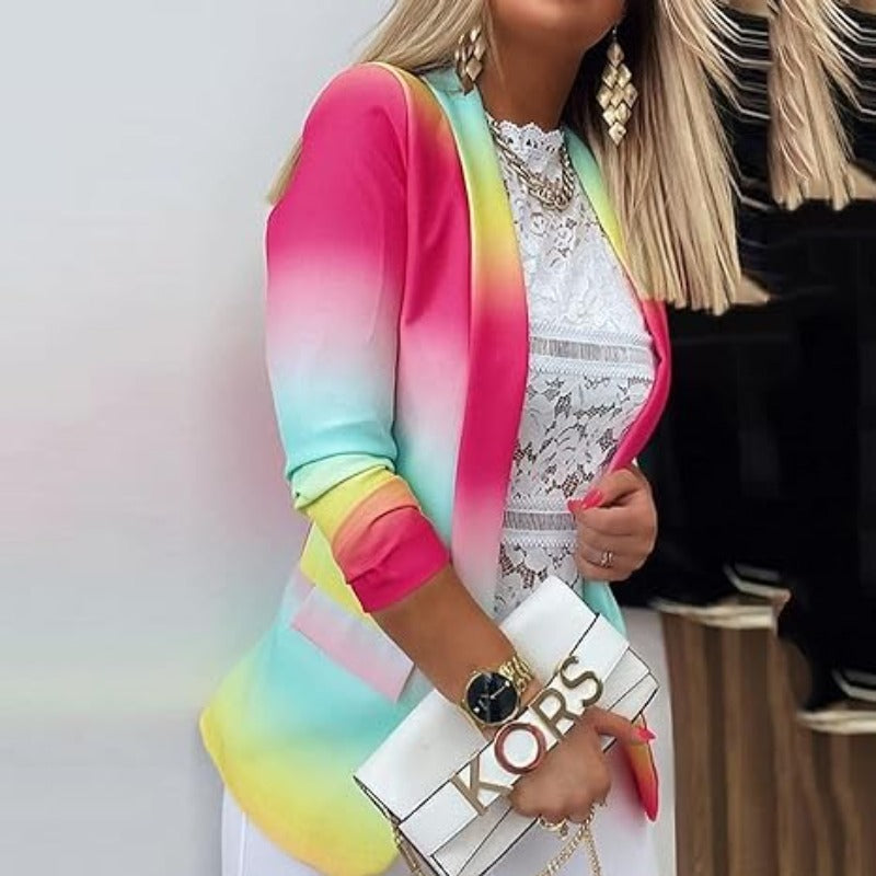 Giacca donna multicolore sfumata, indossata su top in pizzo bianco. Accessori: borsa bianca con logo dorato, orologio nero, orecchini pendenti.