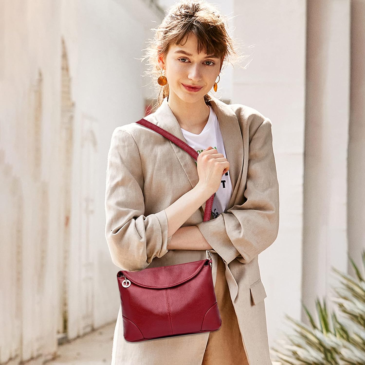 Donna con borsa a tracolla in pelle rossa, elegante e moderna, indossa blazer beige. Accessorio moda femminile, stile casual chic.