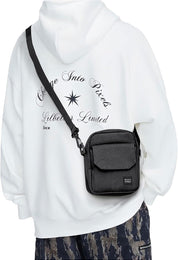 Borsa a tracolla nera su felpa bianca con stampa, moda casual uomo, abbigliamento streetwear, pantaloni mimetici, accessori pratici e versatili.