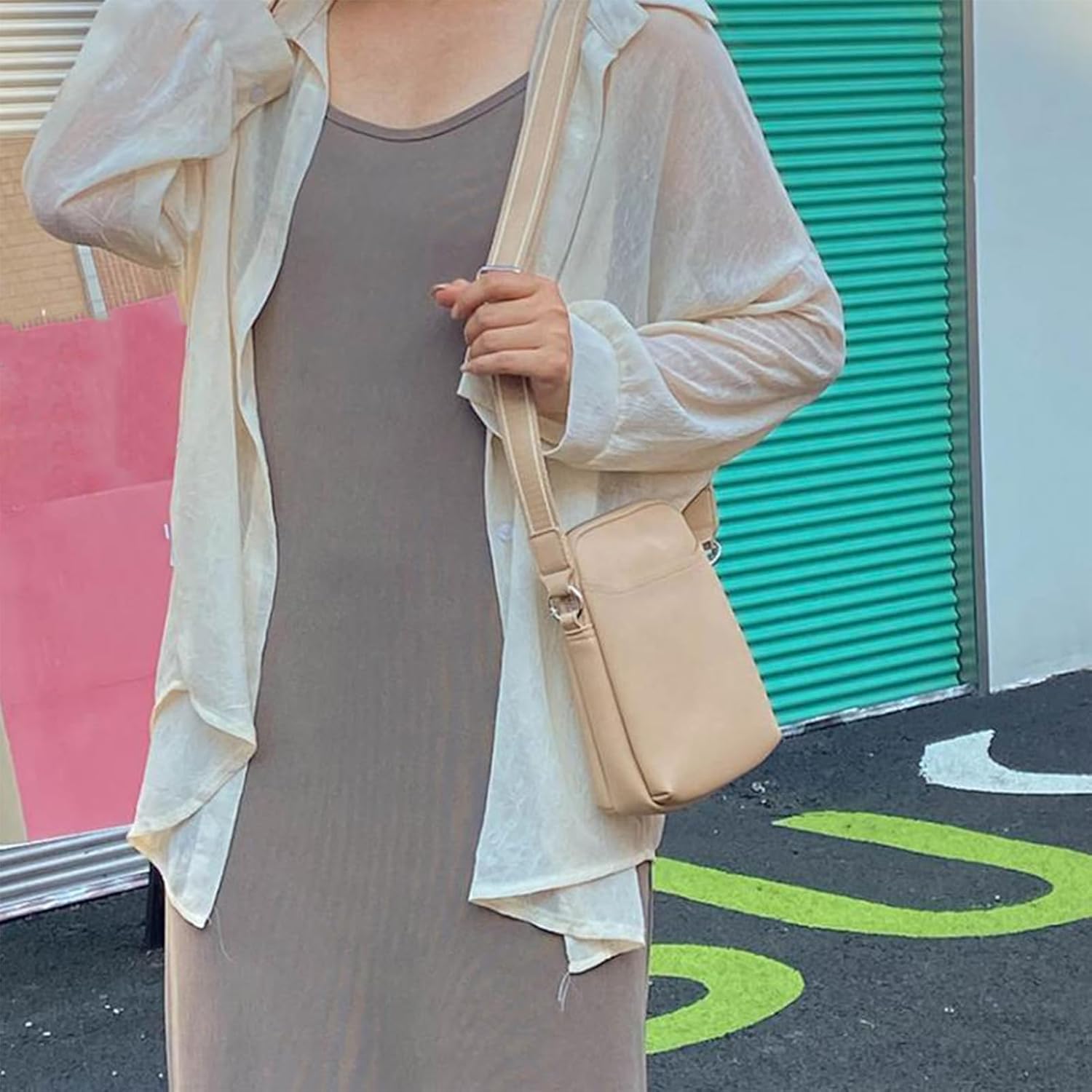 Abito estivo beige con borsa a tracolla in pelle chiara, indossato su sfondo urbano colorato. Moda casual donna, stile estivo elegante.
