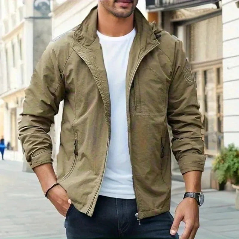 Giacca uomo casual beige, stile militare, con zip e tasche, indossata su t-shirt bianca e jeans. Moda urbana, abbigliamento maschile trendy.