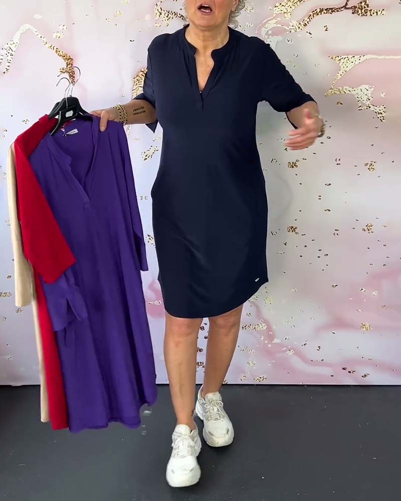 Donna in abito blu scuro con maniche corte, tiene abiti colorati su grucce. Sfondo decorativo rosa. Moda femminile, abbigliamento casual.